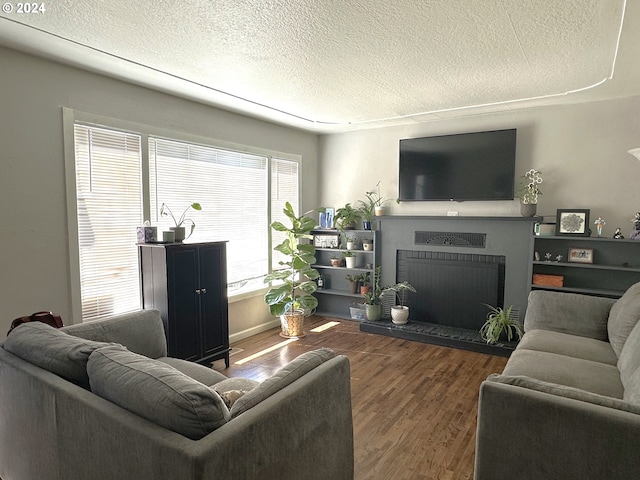 living room featuring dark hardwood / wood-style floors, a textured ceiling, and a brick fireplace