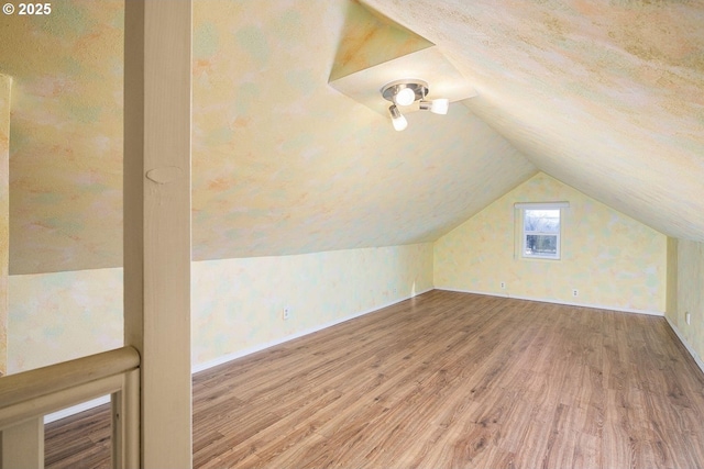 bonus room with vaulted ceiling, wood finished floors, and baseboards