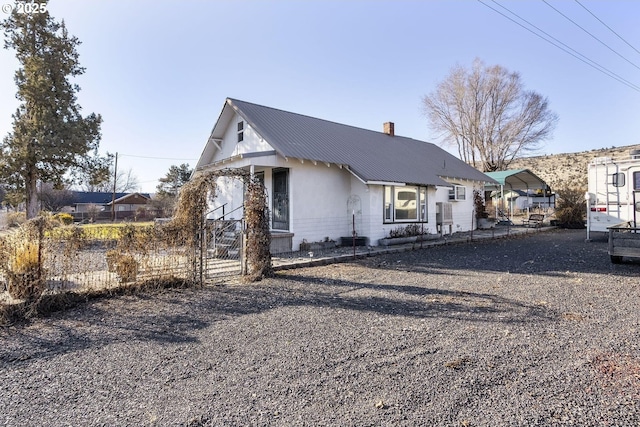 view of front of home with a chimney, fence, and metal roof