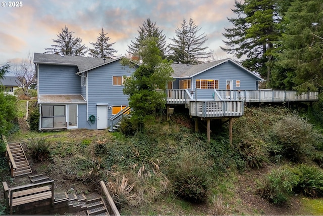 back house at dusk with a wooden deck