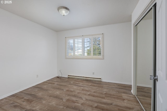 unfurnished bedroom featuring hardwood / wood-style flooring, a baseboard radiator, and a closet