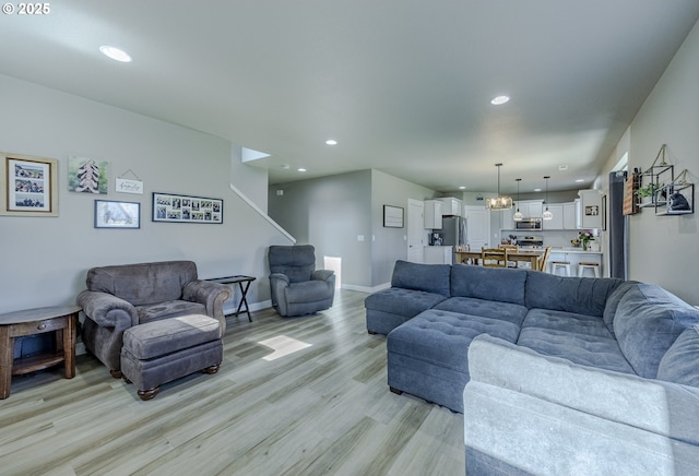 living area featuring recessed lighting, light wood-style flooring, baseboards, and an inviting chandelier