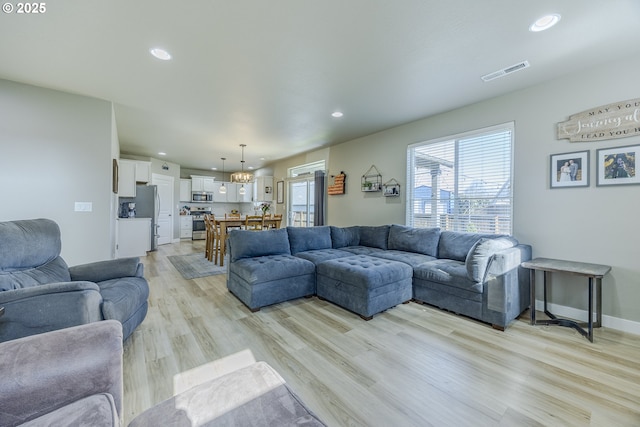 living area with light wood-type flooring, visible vents, and recessed lighting