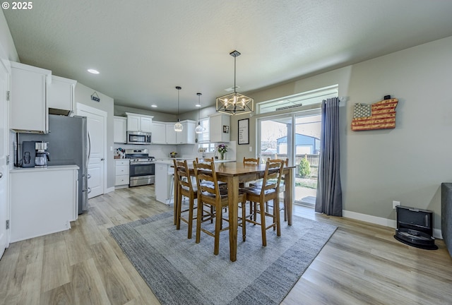 dining space featuring light wood-style floors, baseboards, a textured ceiling, and recessed lighting