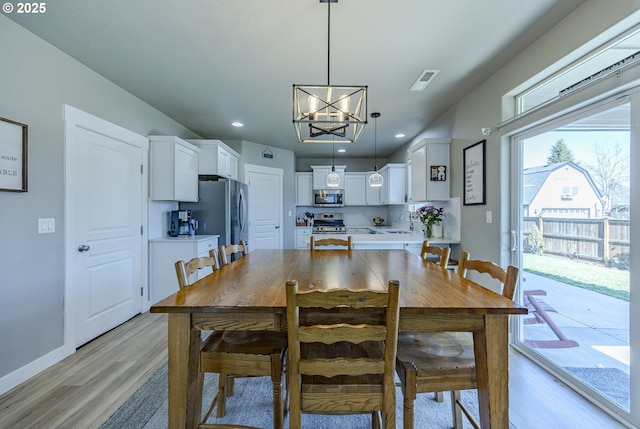 dining room with baseboards, light wood-type flooring, an inviting chandelier, and recessed lighting