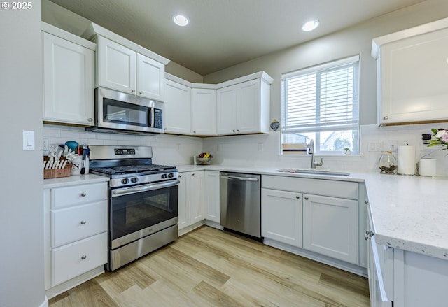 kitchen featuring stainless steel appliances, tasteful backsplash, a sink, and white cabinets