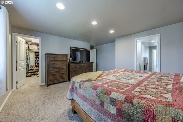 bedroom with light carpet, baseboards, a walk in closet, a textured ceiling, and recessed lighting