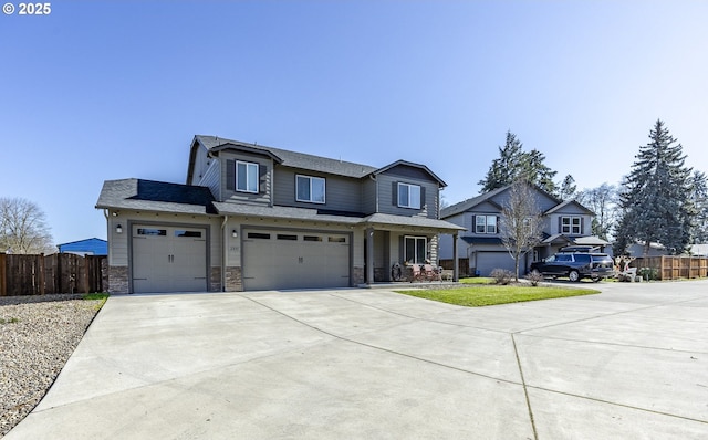 view of front facade with driveway, stone siding, an attached garage, and fence