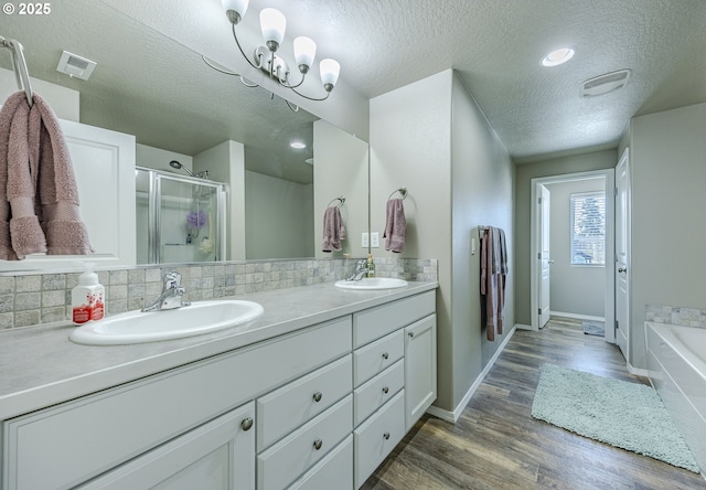 full bath featuring wood finished floors, tasteful backsplash, a sink, and visible vents