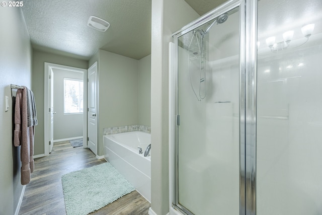 bathroom featuring a shower stall, a textured ceiling, and wood finished floors