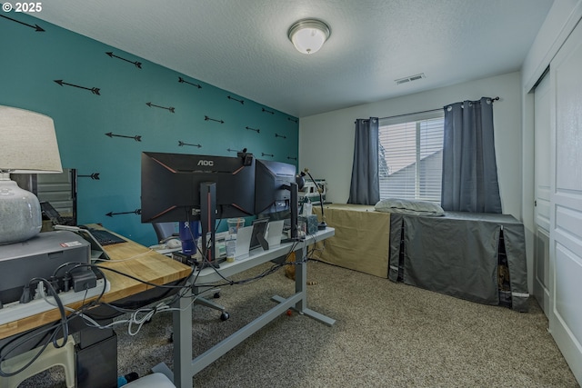 office area with carpet floors, visible vents, and a textured ceiling