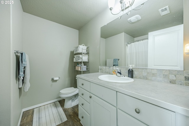 full bath featuring visible vents, toilet, vanity, wood finished floors, and baseboards