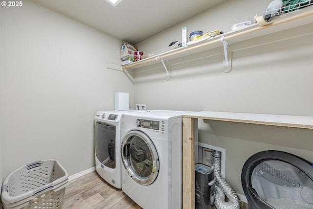 washroom featuring light wood-type flooring, laundry area, baseboards, and separate washer and dryer