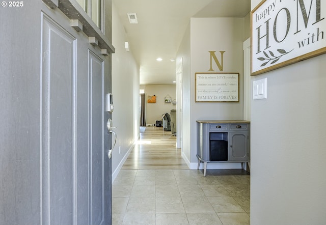 corridor with light tile patterned flooring and baseboards