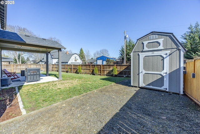 view of yard with an outbuilding, a patio area, a fenced backyard, and a shed