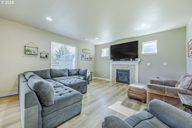 living area with visible vents, a glass covered fireplace, a wealth of natural light, and light wood-style floors