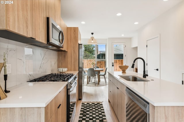 kitchen with a sink, modern cabinets, light brown cabinetry, and stainless steel appliances