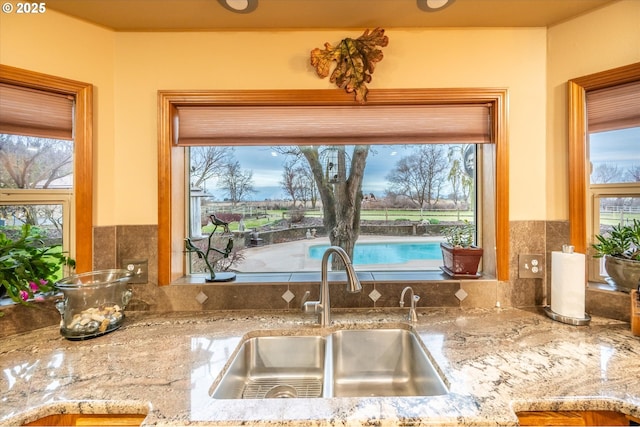 kitchen featuring light stone counters, a sink, and a healthy amount of sunlight