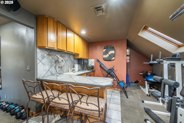 workout room featuring visible vents, lofted ceiling with skylight, and light tile patterned floors