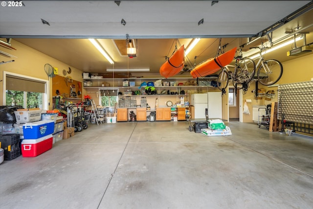 garage with a garage door opener, a workshop area, and freestanding refrigerator