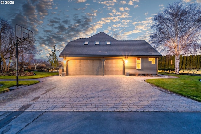 view of front facade featuring a front yard, decorative driveway, and an attached garage