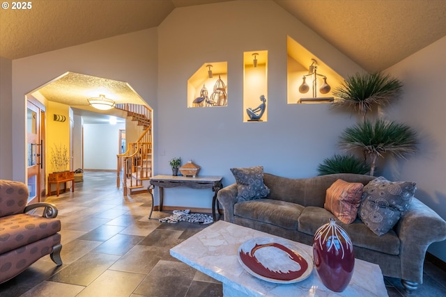 living area with vaulted ceiling, stairway, and a textured ceiling