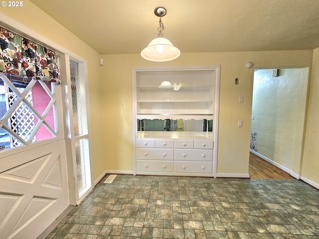 unfurnished dining area featuring baseboards and stone finish flooring