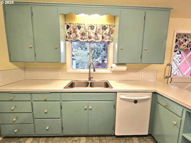 kitchen with white dishwasher, a sink, and light countertops