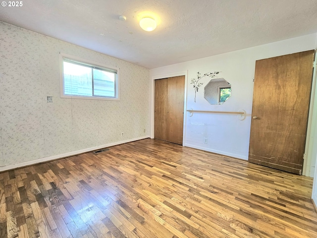 unfurnished bedroom featuring wood-type flooring, baseboards, and a closet