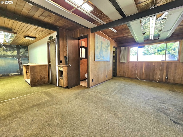 carpeted spare room featuring wooden walls, wood ceiling, and vaulted ceiling with beams