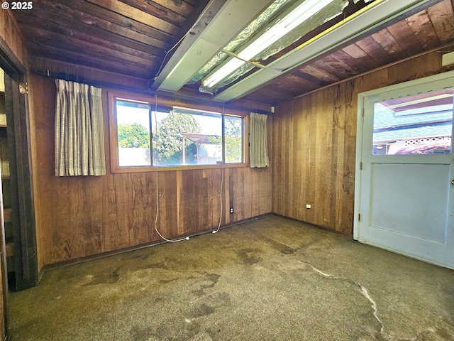unfurnished room featuring carpet floors, wooden walls, and wooden ceiling