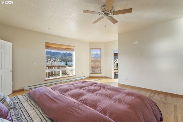 285 W Sunny Sands Rd, Cathlamet, WA 98612 - bedroom with a baseboard heating unit, baseboards, light wood finished floors, ceiling fan, and a textured ceiling