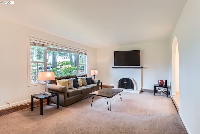 2900 NW 111th Ct, Portland, OR 97229 - carpeted living room with arched walkways, baseboards, and a fireplace with raised hearth