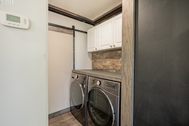 laundry area with cabinet space, washer and clothes dryer, wood finished floors, a barn door, and baseboards