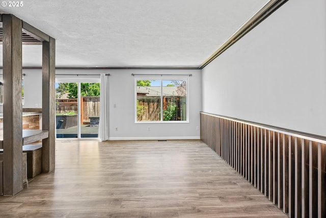unfurnished room with ornamental molding, wood finished floors, and baseboards