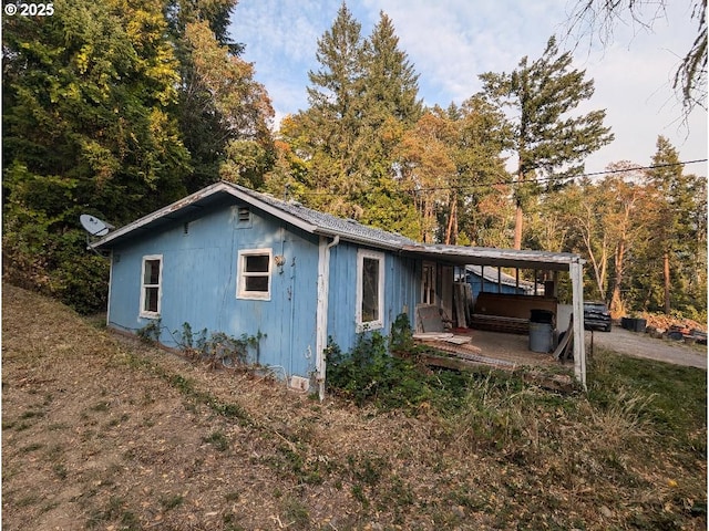 view of side of property with a patio area and a hot tub