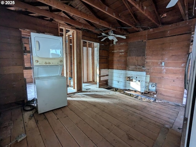 miscellaneous room featuring stacked washer and clothes dryer, ceiling fan, wooden walls, and wood finished floors