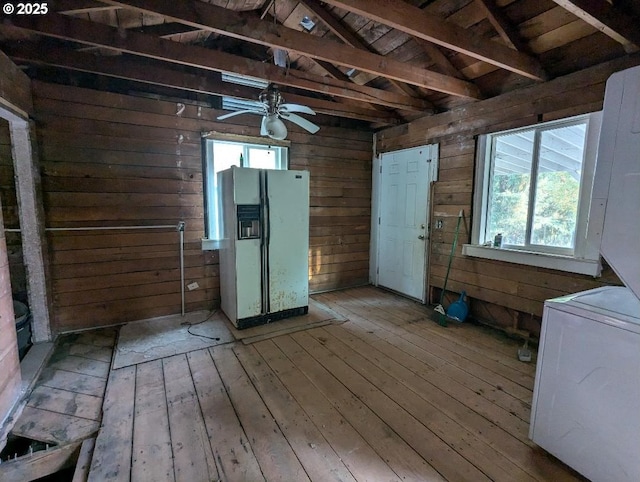 interior space featuring lofted ceiling, wood walls, wood finished floors, a ceiling fan, and washer / clothes dryer