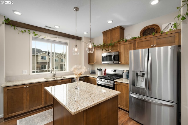 kitchen featuring stainless steel appliances, a sink, visible vents, light stone countertops, and brown cabinetry