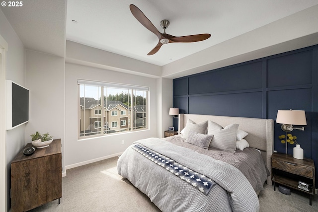 bedroom with light carpet, ceiling fan, a decorative wall, and baseboards