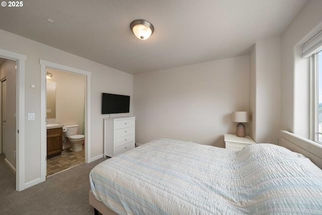 bedroom featuring dark carpet, ensuite bath, and baseboards