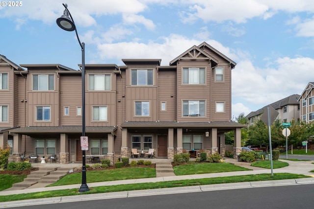 multi unit property featuring stone siding, a porch, and board and batten siding