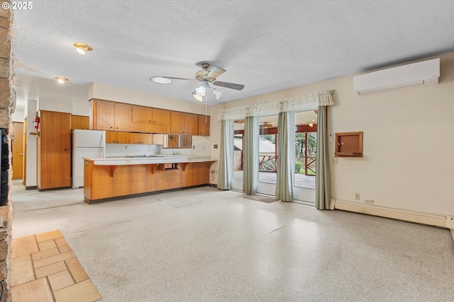 kitchen featuring brown cabinetry, a baseboard radiator, freestanding refrigerator, light countertops, and a wall mounted air conditioner