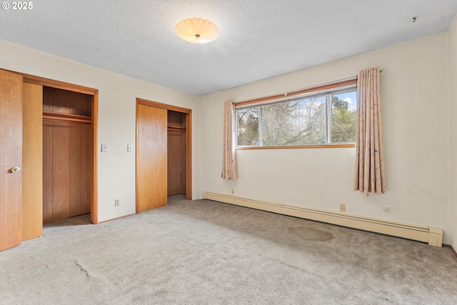 unfurnished bedroom featuring a baseboard radiator, multiple closets, a textured ceiling, and carpet flooring