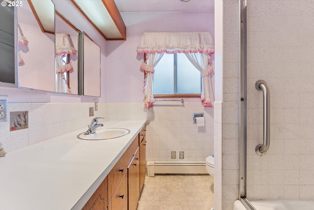 bathroom featuring a wainscoted wall, vanity, baseboard heating, an enclosed shower, and tile walls