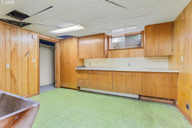 kitchen with light countertops, light floors, brown cabinets, and wood walls