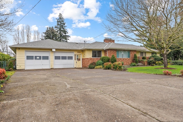 single story home with brick siding, a front yard, a chimney, driveway, and an attached garage