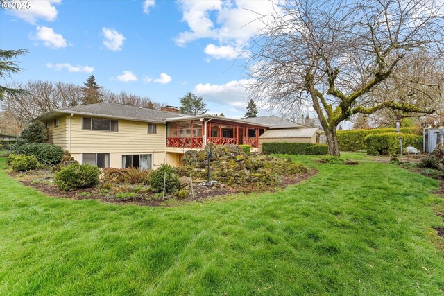 back of property with a lawn, a chimney, and a sunroom