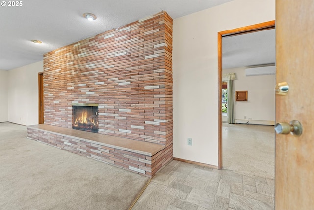 unfurnished living room with a wall unit AC, a brick fireplace, baseboards, and a textured ceiling