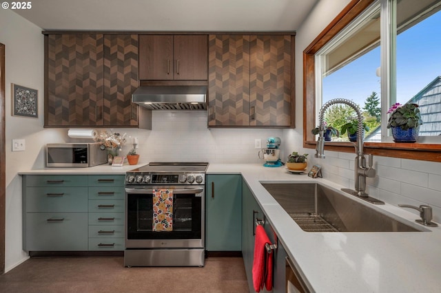 3511 NE Holman St, Portland, OR 97211 - kitchen with stainless steel appliances, wall chimney exhaust hood, decorative backsplash, and light countertops